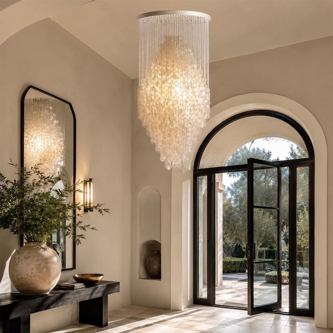 Contemporary organic shaped glass pendant light in a grand entry foyer with arched doors and olive tree.