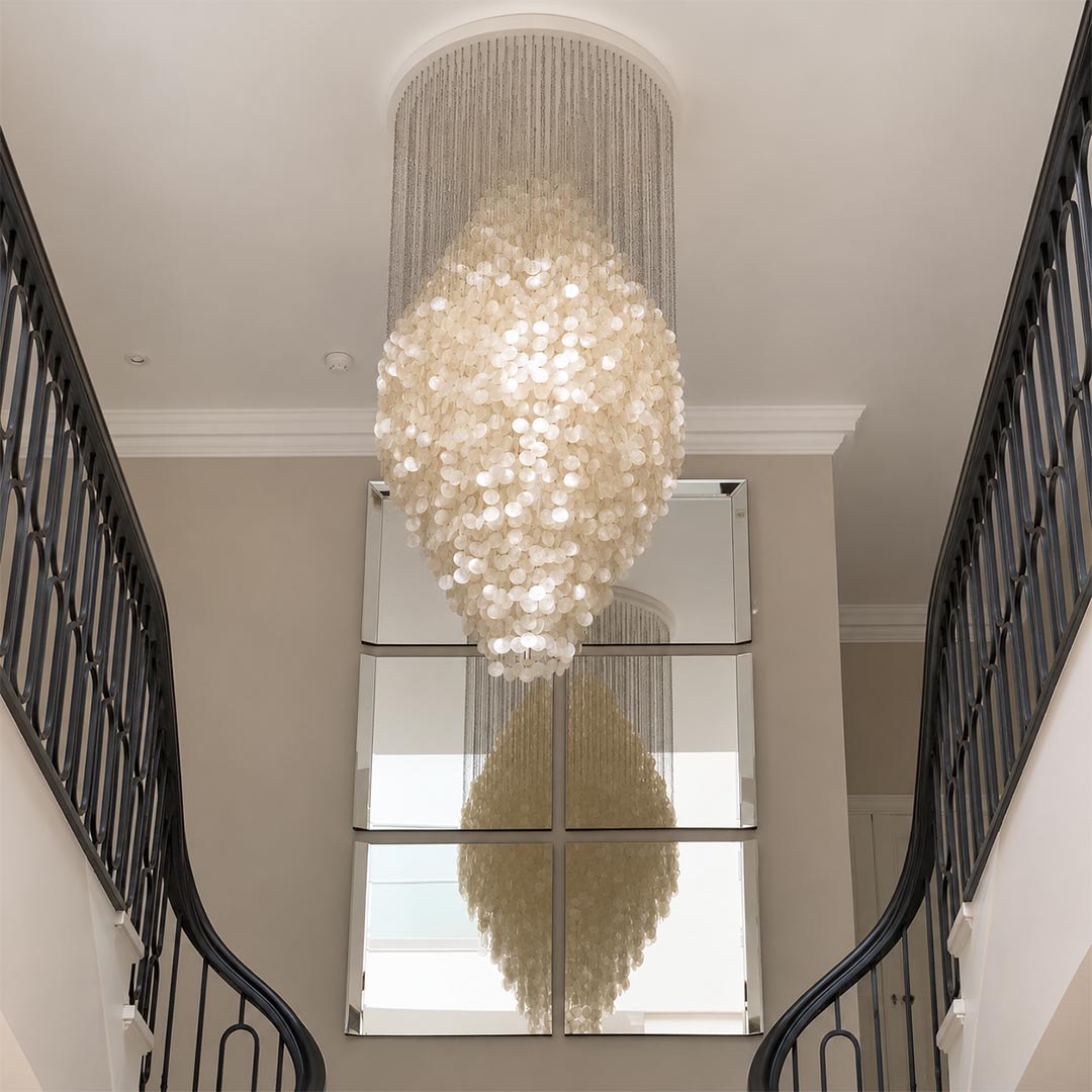 Luxurious contemporary glass pendant light in a modern hallway with natural light and olive trees.