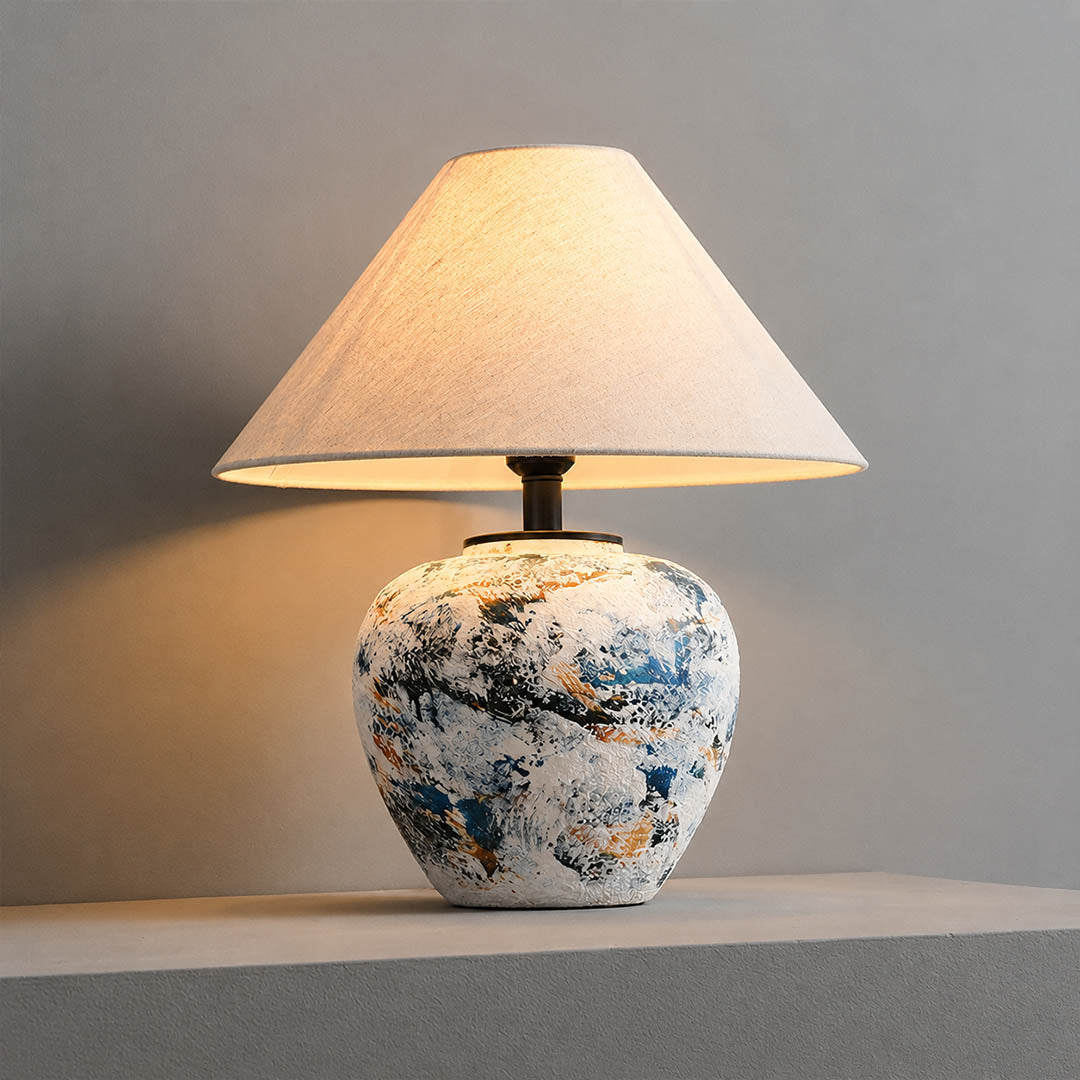 Azzurro ceramic table lamp illuminated warm glow beige fabric shade blue white ceramic base cozy white background front view