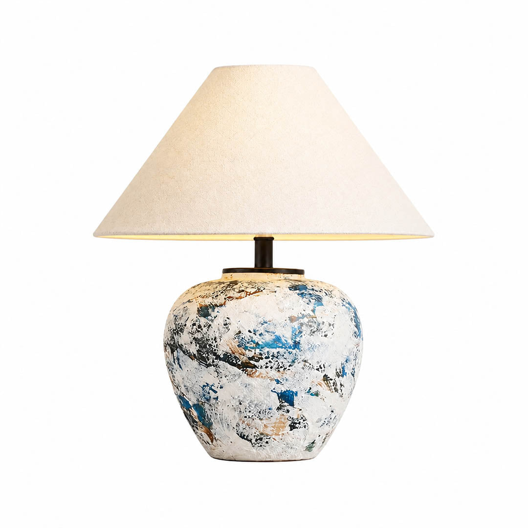 Azzurro ceramic table lamp illuminated warm glow beige fabric shade blue white ceramic base cozy white background front view
