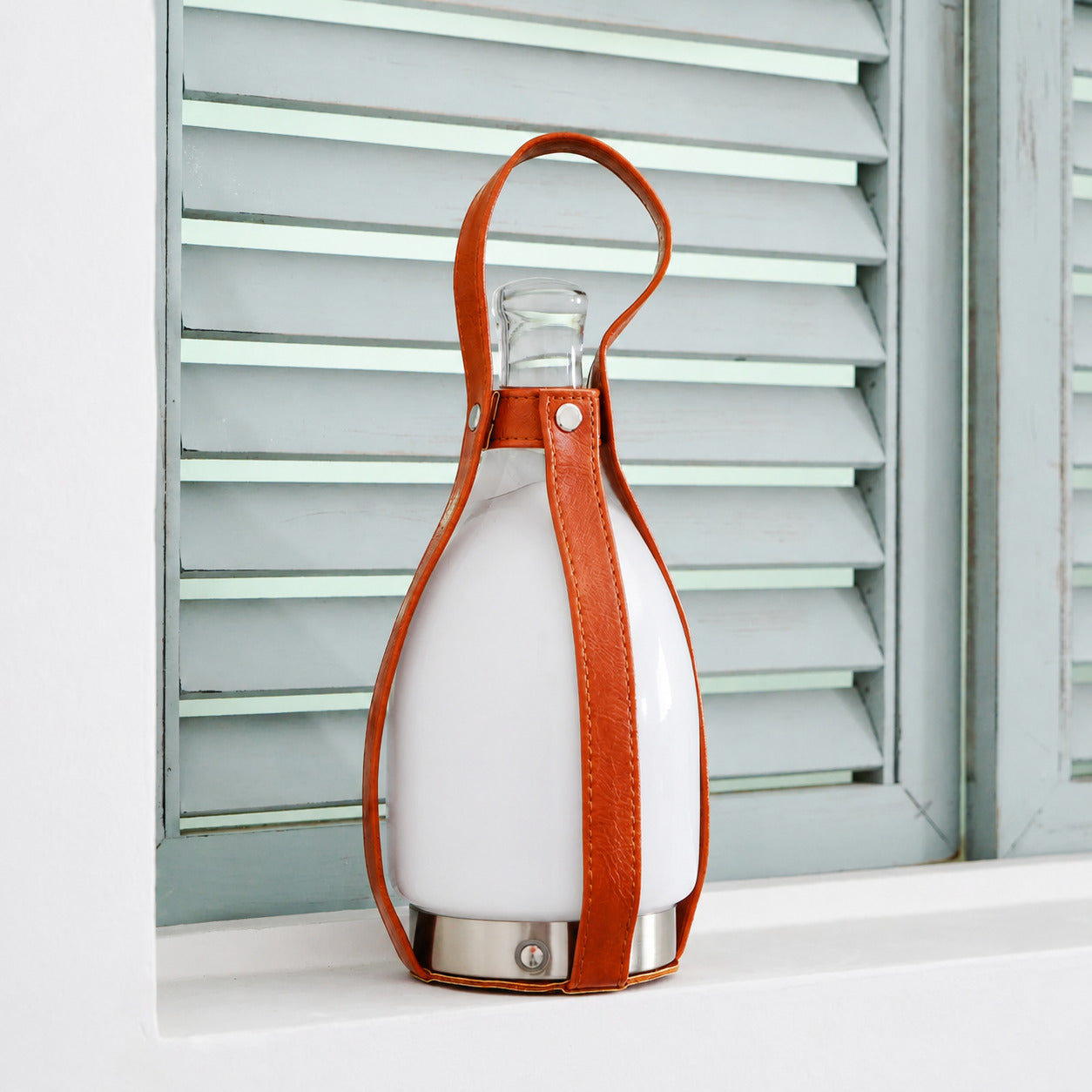 Belle portable table lamp glass bottle body leather handle brass rivets detail close up craftsmanship