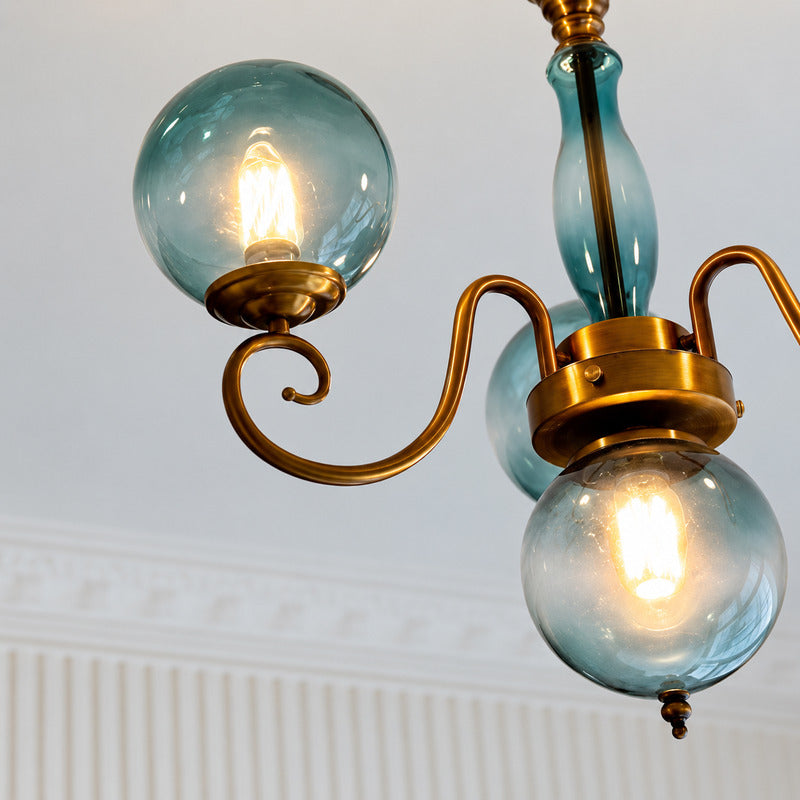 Warm light glowing through the colored glass globes of the Boule chandelier
