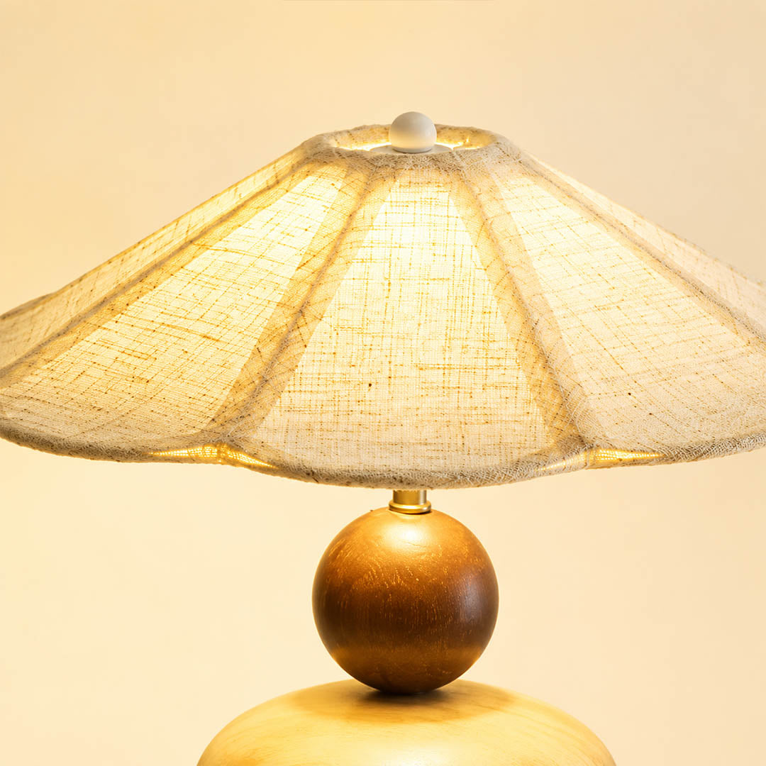Cairn wood table lamp illuminated pleated linen shade warm diffused wide glow soft light detail close up cozy