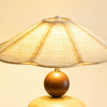Cairn wood table lamp illuminated pleated linen shade warm diffused wide glow soft light detail close up cozy