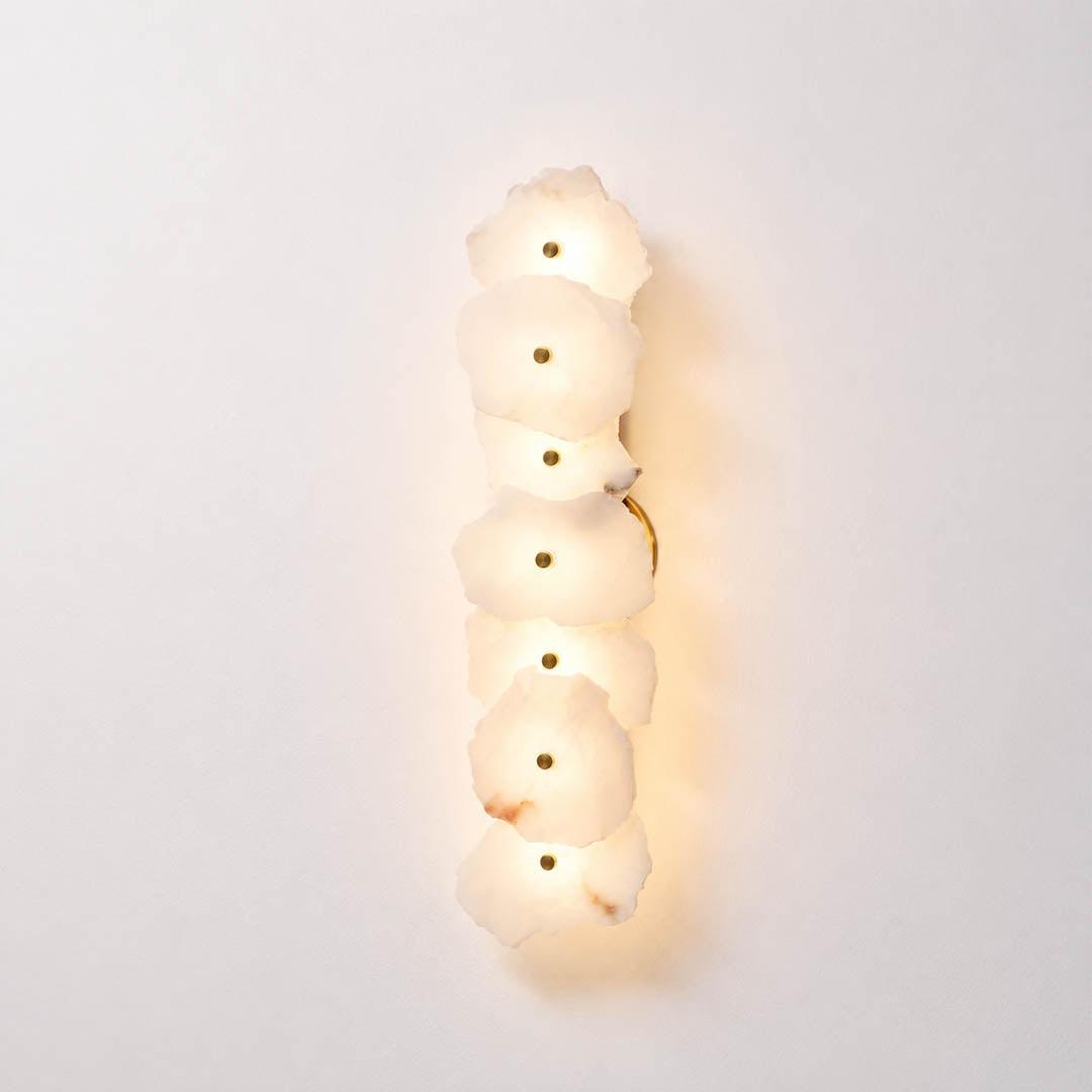 Calcaria alabaster wall light illuminated warm glow translucent natural stone gold organic soft radiance white background