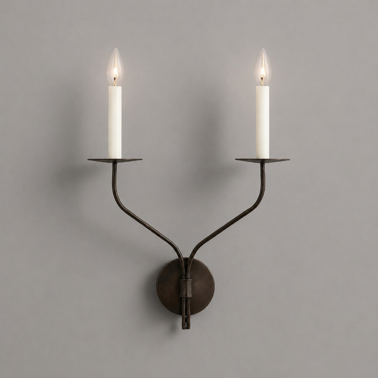 Candela wall sconce two light matte black finish candle style dual exposed E14 bulbs twin curved arms wide backplate minimalist white background front view