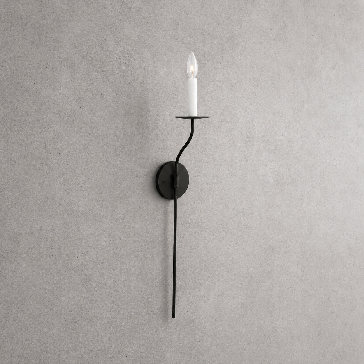 Candela wall sconce tall single light matte black finish candle style exposed E14 bulb slim curved arm round backplate minimalist vintage white background front view