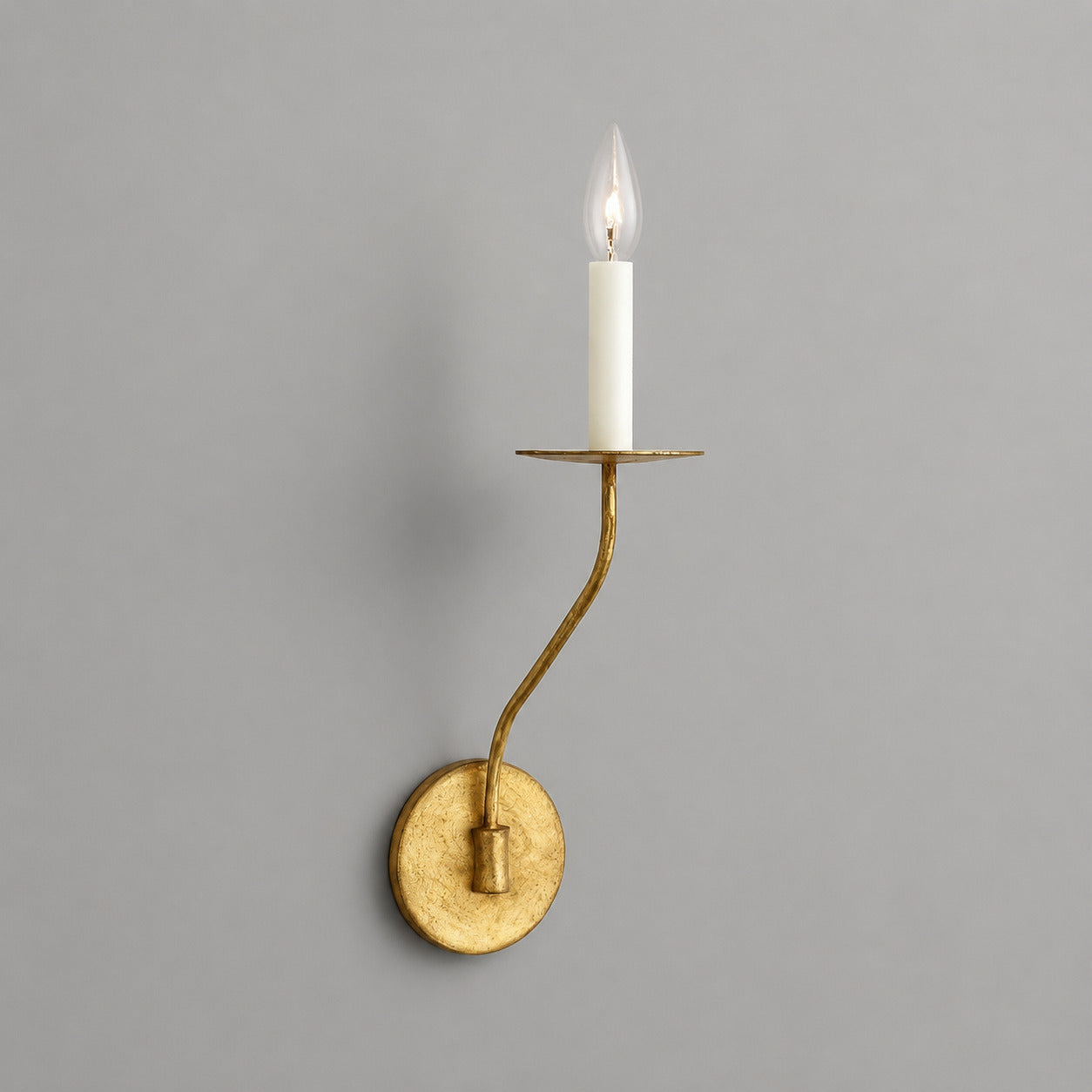 Candela wall sconce short single light aged brass finish candle style exposed E14 bulb compact curved arm round wall plate vintage white background front view