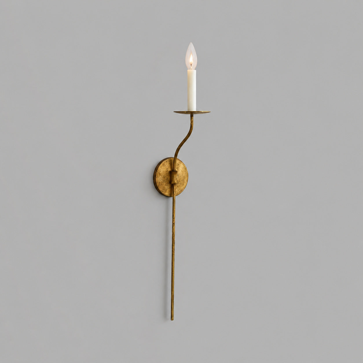 Candela wall sconce tall single light aged brass finish candle style exposed E14 bulb slim curved arm round wall plate vintage mid century white background front view