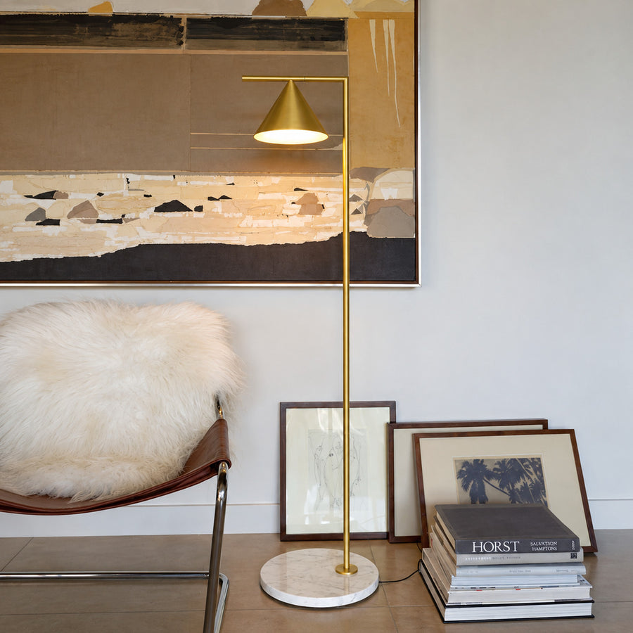 Girevole marble floor lamp angled over an armchair to direct warm reading light in a corner