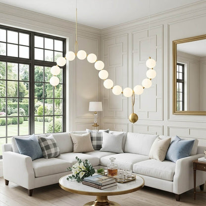 Cascadia horizontal chandelier above long dining table pearl globes warm glow elegant interior