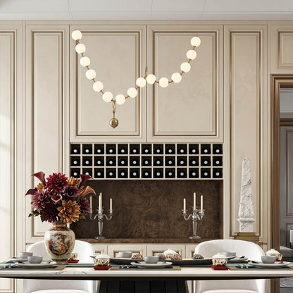 Cascadia horizontal chandelier above long dining table pearl globes warm glow elegant interior