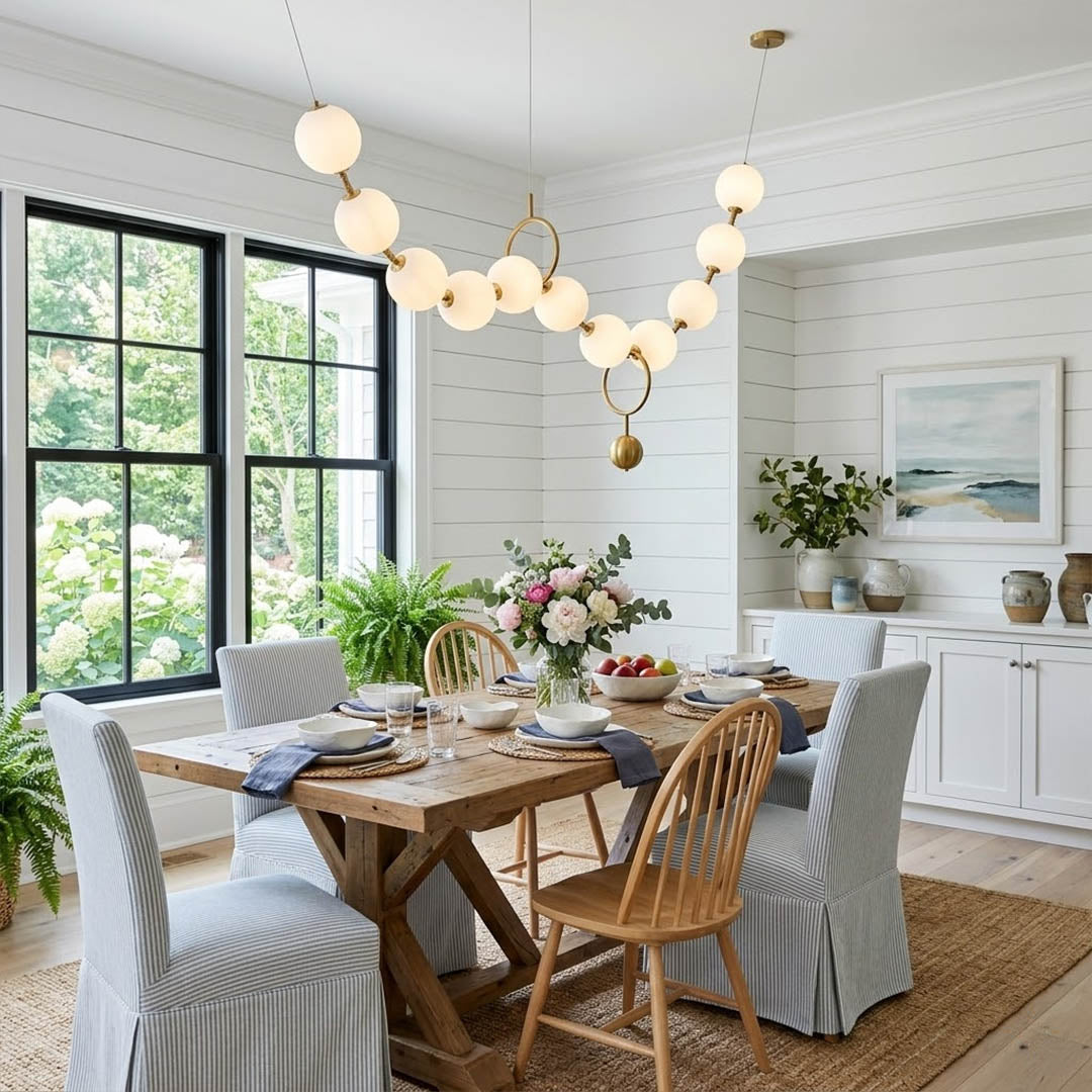 Cascadia horizontal chandelier above long dining table pearl globes warm glow elegant interior