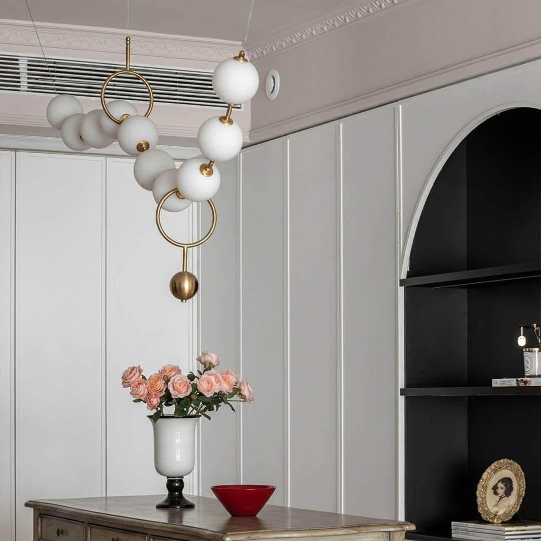 Cascadia horizontal chandelier above long dining table pearl globes warm glow elegant interior