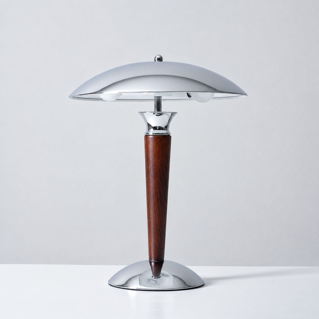 Casco table lamp in chrome and walnut standing on a bedside nightstand with a warm downward glow