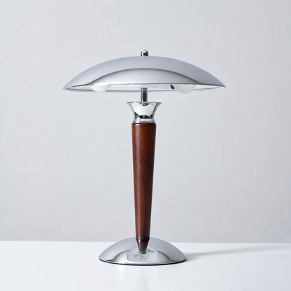 Casco table lamp in chrome and walnut standing on a bedside nightstand with a warm downward glow