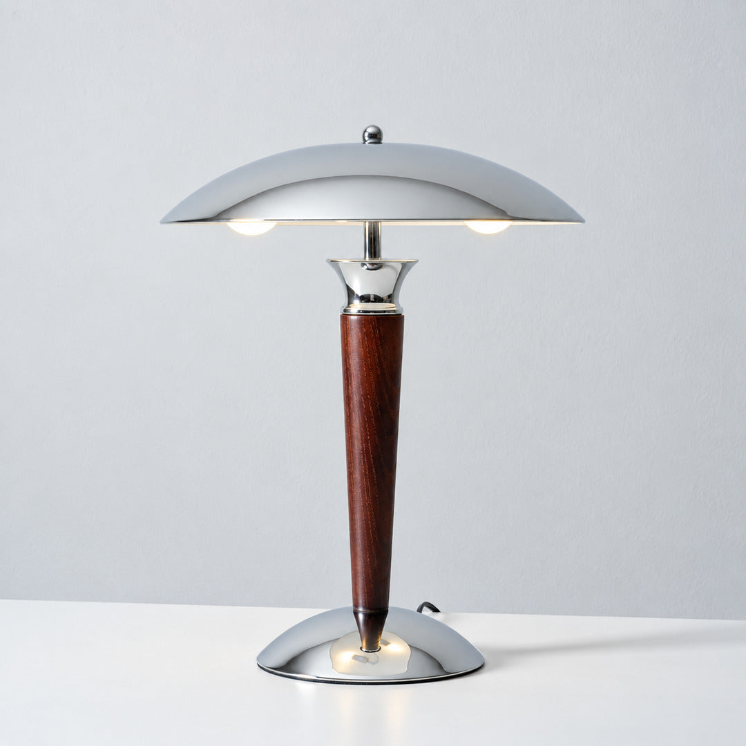 Warm light reflecting downward from the chrome dome shade of the Casco table lamp across a desk