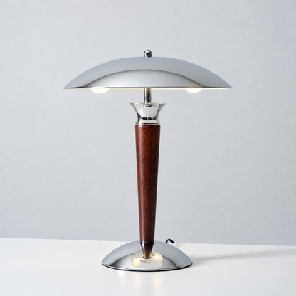 Warm light reflecting downward from the chrome dome shade of the Casco table lamp across a desk