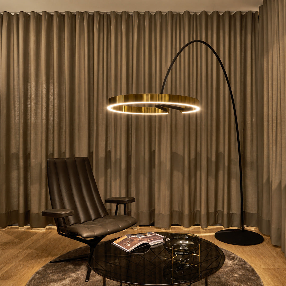 Cerchio halo ring floor lamp casting a soft warm glow over a corner reading chair