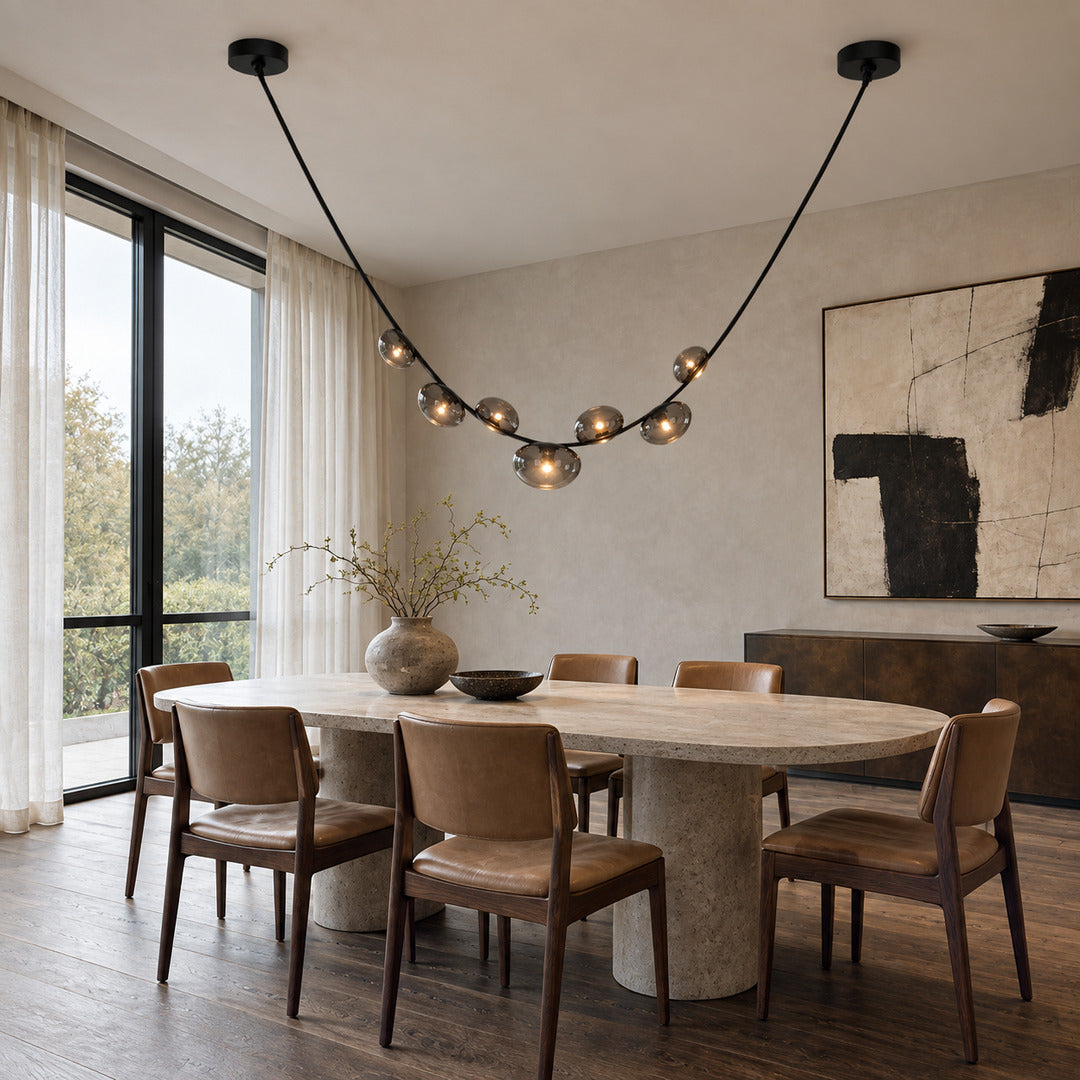 Cinghia leather arc chandelier casting a warm glow over a long dining table