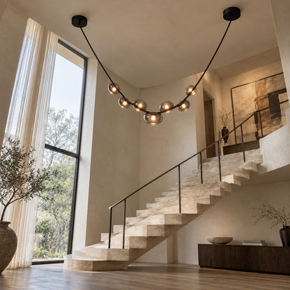 Cinghia leather arc chandelier suspended in an open staircase stairwell