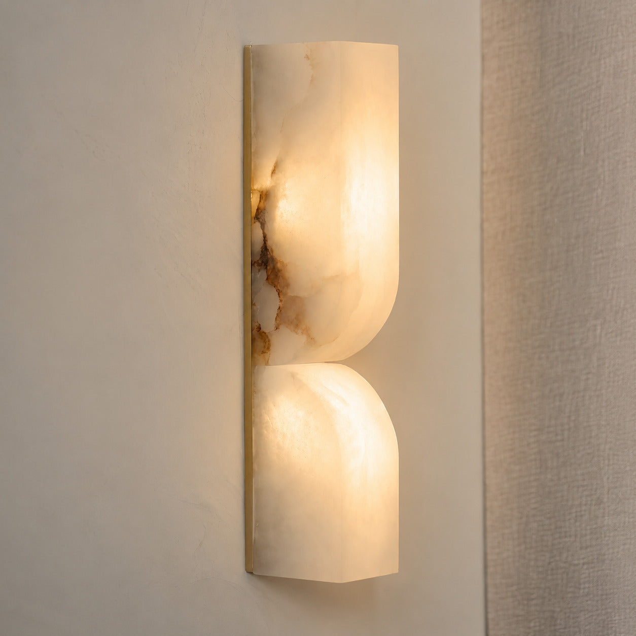 Contatto alabaster wall sconce illuminated glowing veining warm soft radiance translucent carved stone detail close up quiet luxury