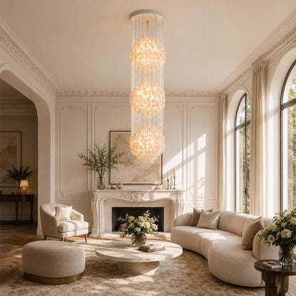 Three-tier Coralia FUN tall style staircase shell chandelier in a bright, elegant living room with arched windows.