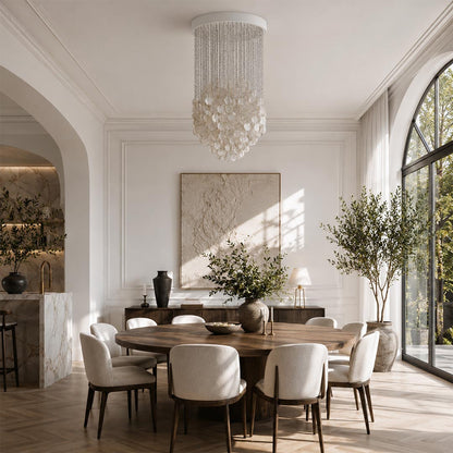 Modern Coralia FUN shell chandelier illuminating an organic modern dining room with a round wooden table.