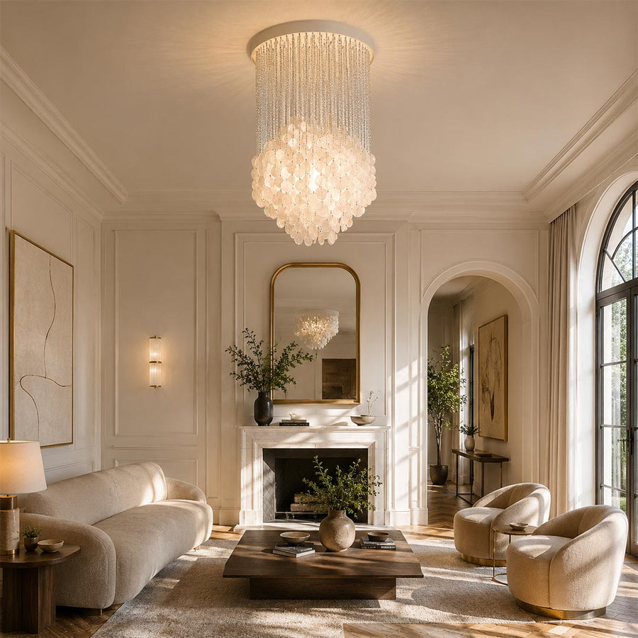 Coralia FUN shell pendant lighting hanging in a cozy wabi-sabi living room with a stone fireplace and cream chairs.