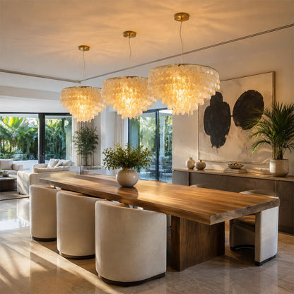 Three Coraline capiz shell wind chime chandeliers hung in a row above a long wooden dining table