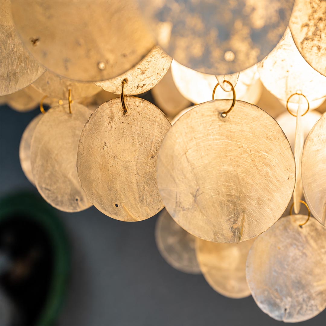 Detailed texture of handcrafted natural capiz sea shell discs on the Coraline wind chime chandelier