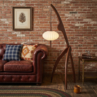 Cygnus walnut wood floor lamp behind sofa living room long arm reaching over seating warm silk glow transitional interior