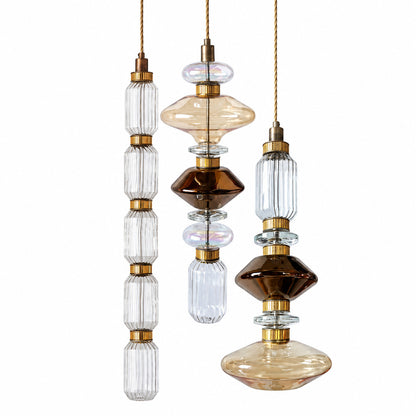 Danza glass pendant light cluster with sculptural glass shades and gold rods glowing warm over a dining table