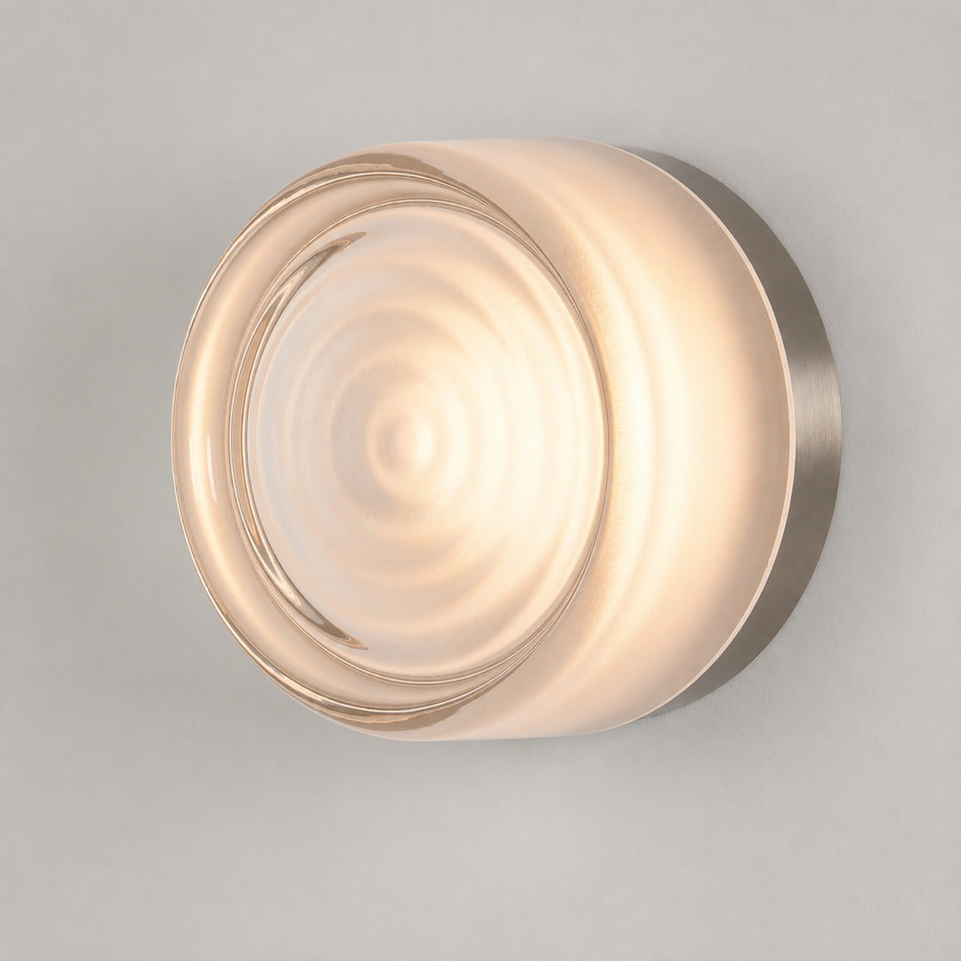 Model B concentric-ring white glass Demi wall sconce with textured front detail glowing warm