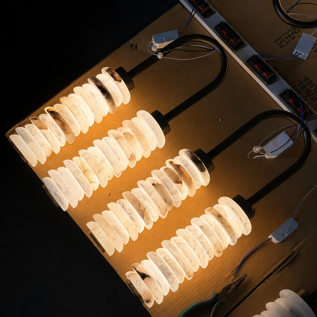 Warm integrated LED glow diffusing through the ribbed alabaster columns of the Duetto wall sconce