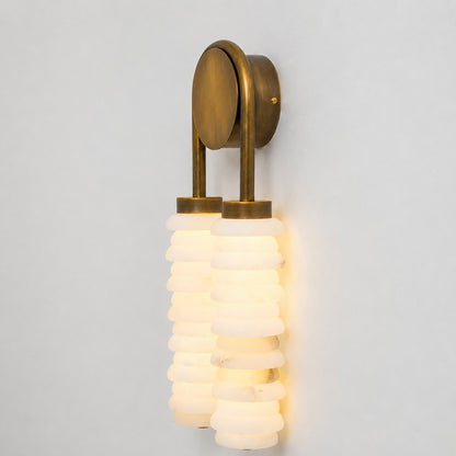 Warm integrated LED glow diffusing through the ribbed alabaster columns of the Duetto wall sconce