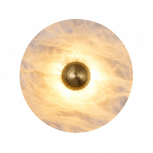 Eclisse alabaster wall sconce with a round natural stone disc and fluted brass accent glowing warm on a wall