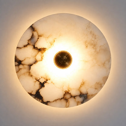 Hidden warm LED glow diffusing softly through the alabaster disc of the Eclisse wall sconce