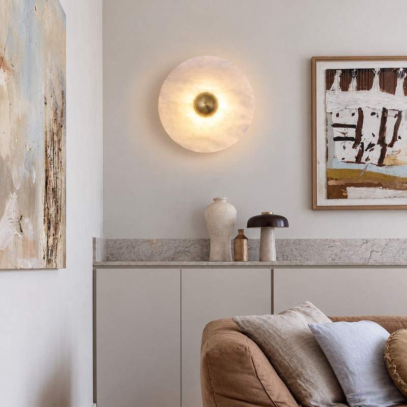 Eclisse alabaster wall sconce welcoming guests with a warm round glow above an entry console