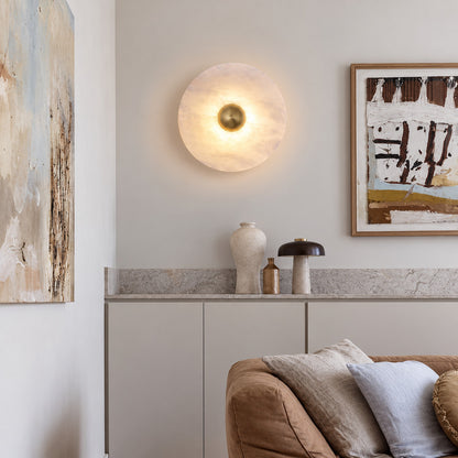 Eclisse alabaster wall sconce welcoming guests with a warm round glow above an entry console