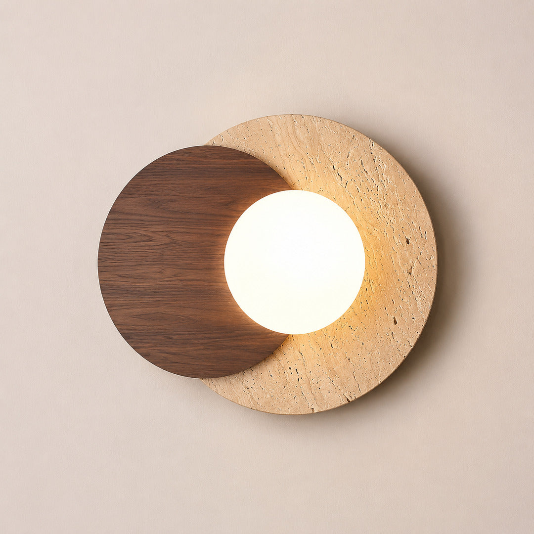 Eclisse travertine wall sconce illuminated warm even glare-free glow white glass globe travertine wood white background