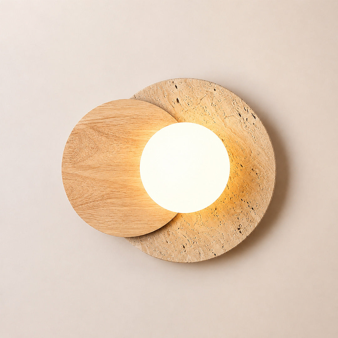 Eclisse travertine wall sconce illuminated warm even glare-free glow white glass globe travertine wood white background