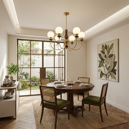Mid-century modern dining space featuring an Estelle Glass Globe Chandelier hanging above a round walnut table and cane chairs by Stuber Lighting.