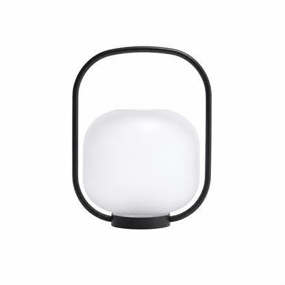 Falo portable lantern with a glass shade and carry handle glowing warm on an outdoor patio table