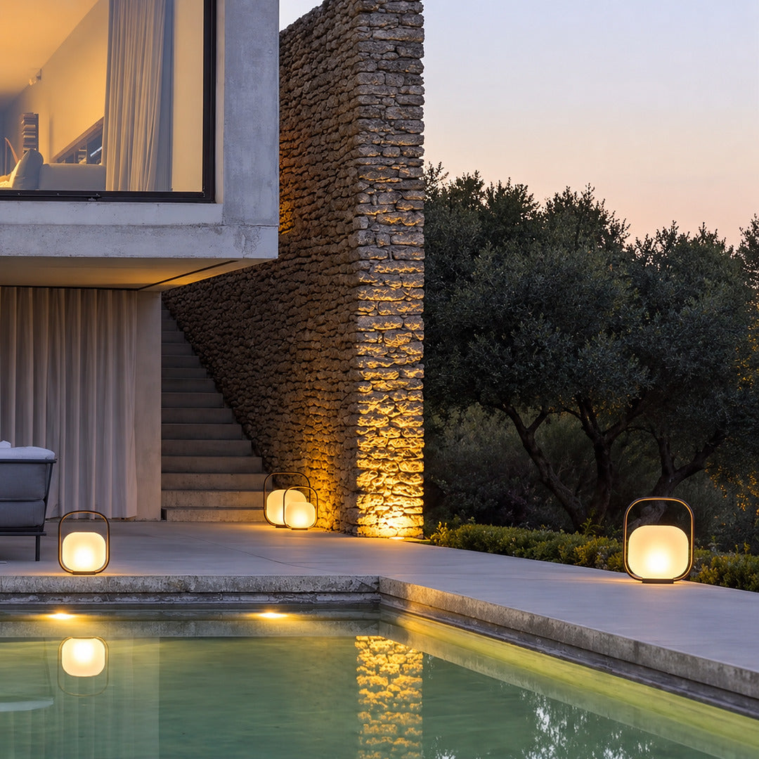 Falo portable lantern on a poolside table casting a warm evening glow