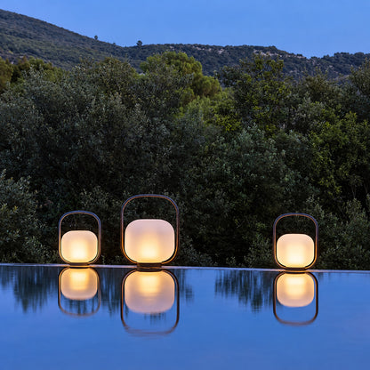 Falo portable lantern on a poolside table casting a warm evening glow