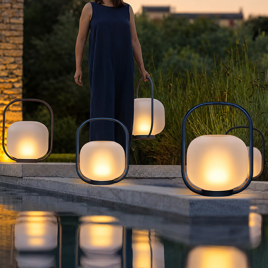 Falo portable lantern on a poolside table casting a warm evening glow
