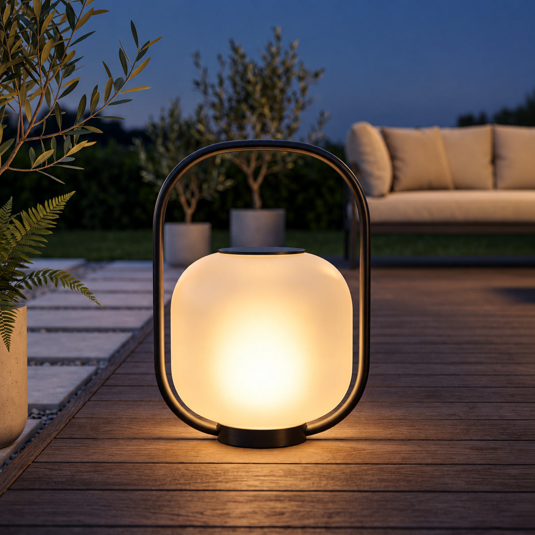 Falo portable lantern glowing warmly on a patio dining table at dusk