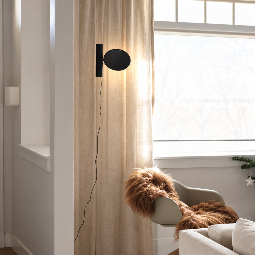 Filo LED disc aimed over a lounge chair to light an open book in a quiet reading corner