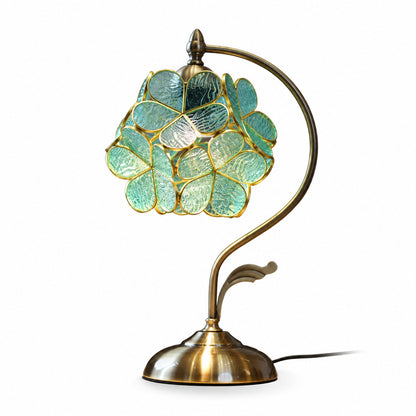 Foglia glass table lamp in green and gold standing on a bedside nightstand with a warm glow